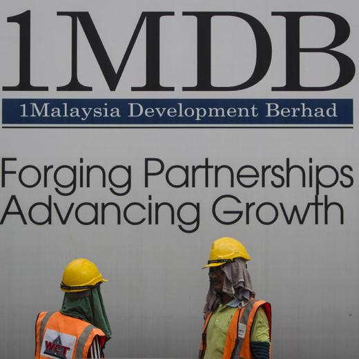 In this May 14, 2015 file photo, construction workers chat in front of a billboard for state investment fund 1 Malaysia Development Berhad (1MDB) at the fund's flagship Tun Razak Exchange development in Kuala Lumpur, Malaysia. Goldman Sachs reaches $3.9 billion settlement with Malaysia over scandal-plagued 1MDB sovereign wealth fund. (AP Photo/Joshua Paul, File)