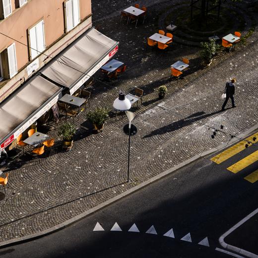Une personne marche devant la terrasse vide du restaurant "Le Byblos" en fin de journee lors de la crise du Coronavirus (Covid-19) le mardi 12 mai 2020 a Lausanne. (KEYSTONE/Jean-Christophe Bott)