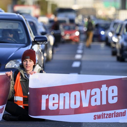 Climate activist sit down in the road during the "Renovate Switzerland" a roadblock action, A1a freeway, in Lausanne, Switzerland, Monday, April 11, 2022. (KEYSTONE/Laurent Gillieron)