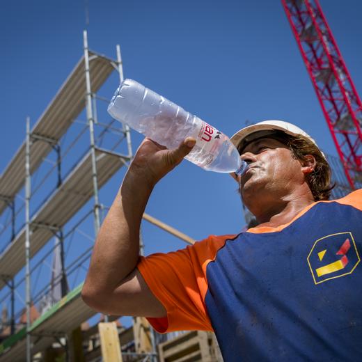 Un ouvrier de la construction boit de l?eau sur un chantier ce mercredi 26 juin 2019 a Lausanne. Le mercure devrait atteindre 38 degres ce mercredi. Le pic de canicule est attendu pour demain. Des mesures exceptionnelles sont prises sur les chantiers vaudois de la construction a cause de la canicule. Le travail pourra etre arrete entre 13h et 17h, indiquent mercredi la Federation vaudoise des entrepreneurs (FVE) et le syndicat Unia. (KEYSTONE/Jean-Christophe Bott)