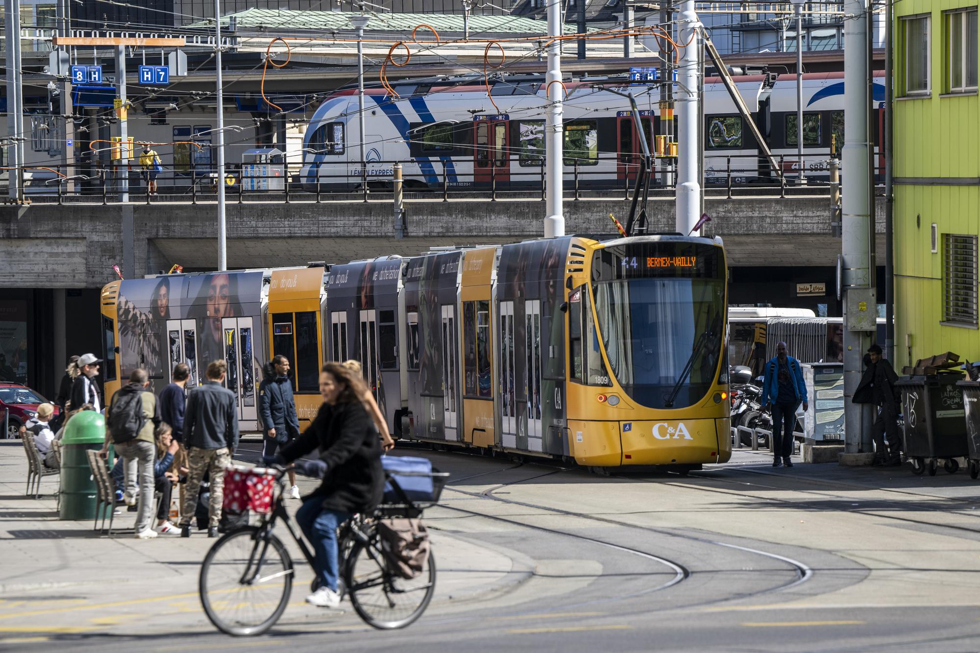 Une personne a velo passe devant un train FLIRT Leman Express et un tram (Tramway) des Transports publics genevois (TPG) sont photographies a Cornavin, ce mercredi 21 septembre 2022 a Geneve. Le CEVA, Liaison ferroviaire Cornavin, Eaux-Vives, Annemasse et du Leman Express et de Lemanis. (KEYSTONE/Martial Trezzini).