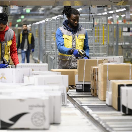 Des employes de la poste suisse trient des paquets fragile au centre colis de La Poste ce jeudi 15 decembre 2022 a Daillens, Vaud. Pendant les jours de pointe avant Noel, le volume depasse souvent les 230 000 colis. La capacite de tri maximale s'eleve a 19 000 colis par heure. En 2021, la Poste a trie au total 45,2 millions de colis a Daillens. (KEYSTONE/Laurent Gillieron)