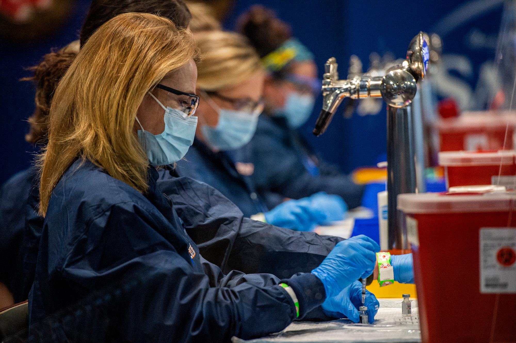 Medical staff workers prepare syringes with doses of Covid-19 vaccine while working behind beer taps at Fenway Park in Boston, Massachusetts on January 29, 2021. - Fenway Park is opening as a mass vaccination site expected to vaccinate over a thousand people a day, with the Pfizer-BioNTech COVID-19 Vaccine, as the site ramps up starting next week with an estimated five-hundred people a day. The site is a cooperation between the Commonwealth of Massachusetts, Cambridge-based health tech company CIC Health and the Red Sox. (Photo by Joseph Prezioso / AFP)