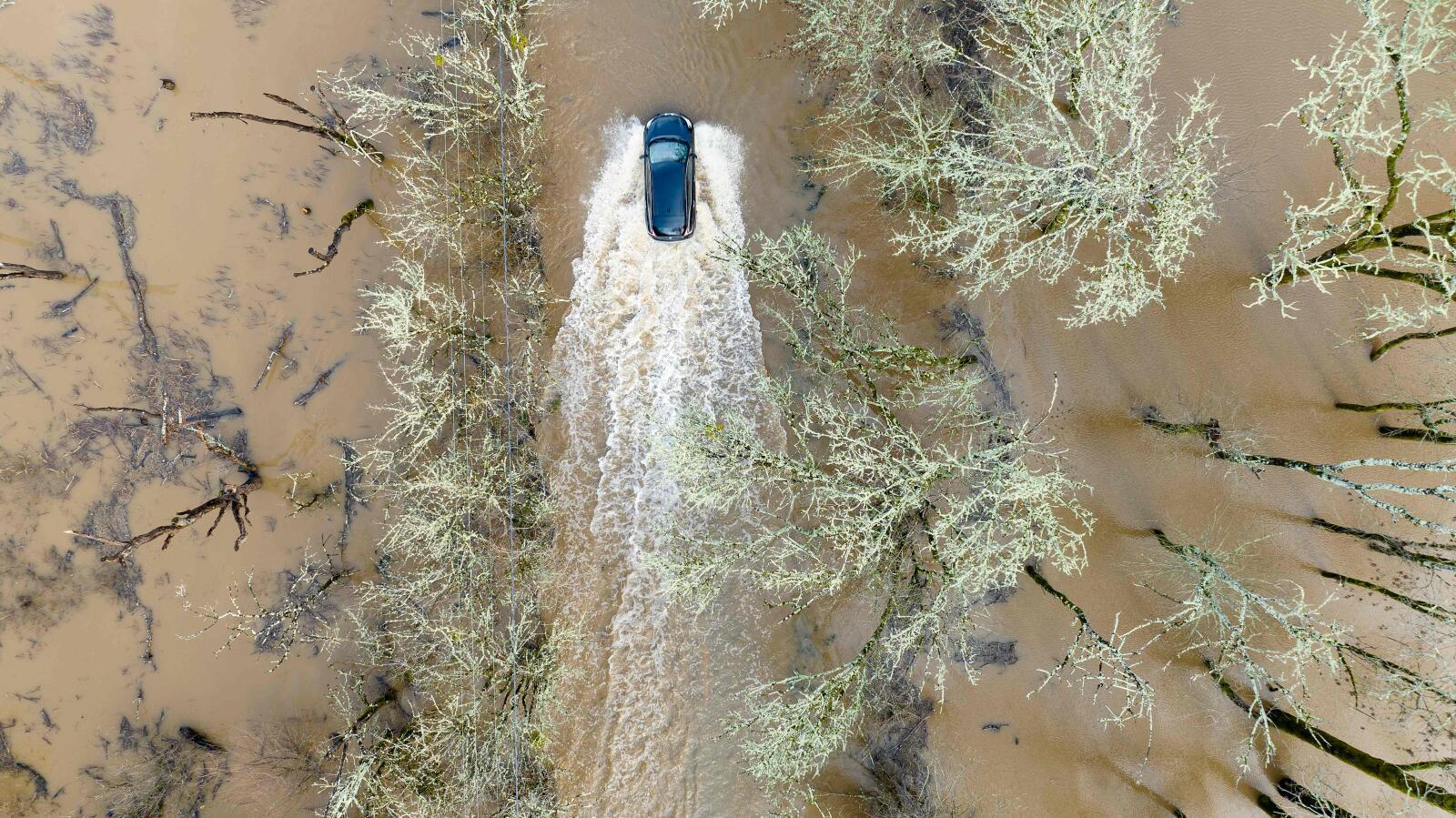 TOPSHOT - A vehicle drives on a flooded road in Sebastopol, California, on January 5, 2023. - Excessive rain, heavy snow and landslides are expected to wallop California through Thursday as a series of winter storms rip across the western US coast, prompting Governor Gavin Newsom to declare a state of emergency. (Photo by JOSH EDELSON / AFP)