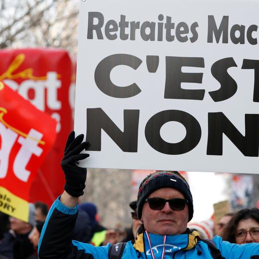 A demonstrator holds a placard which reads "No to Macron's pensions reform" during a demonstration against French government's pensions reform plans in Paris as part of another day of nationwide strikes and protests in France, January 24, 2020. REUTERS/Christian Hartmann