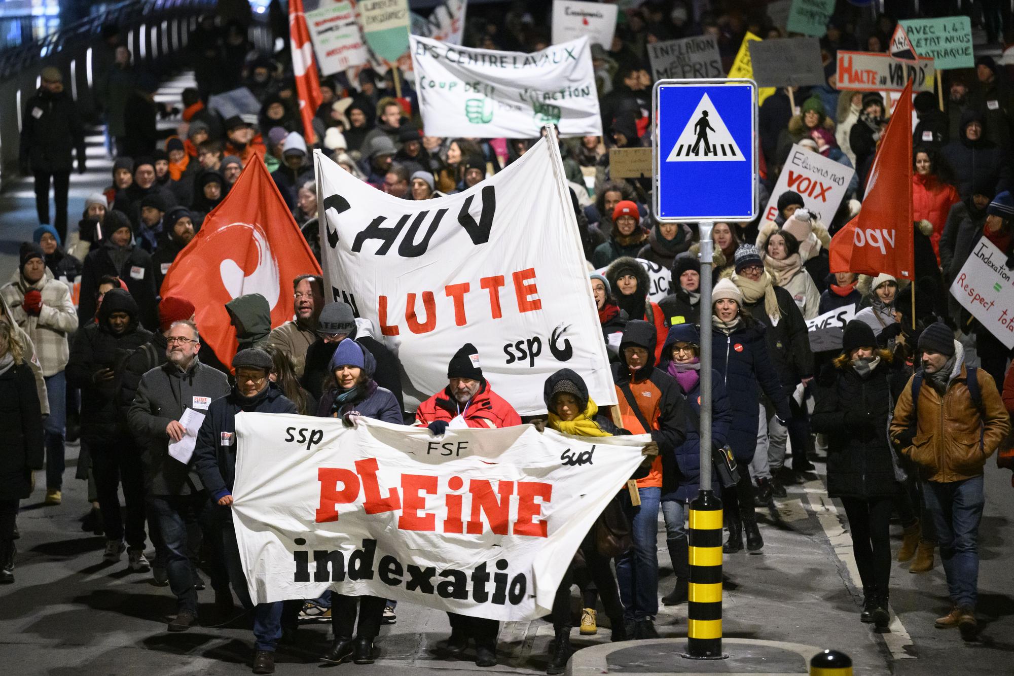 Des employes de l'Etat de Vaud brandissent des pancartes devant le siege du gouvernement vaudois, le chateau Saint-Maire, lors de la manifestion qui fait suite a la journee d'actions et de greve de la fonction publique vaudoise, des salaries des secteurs publics a l'appel de leurs syndicats (FSF, SSP, SUD) ce lundi 23 janvier 2023 a Lausanne. (KEYSTONE/Laurent Gillieron)