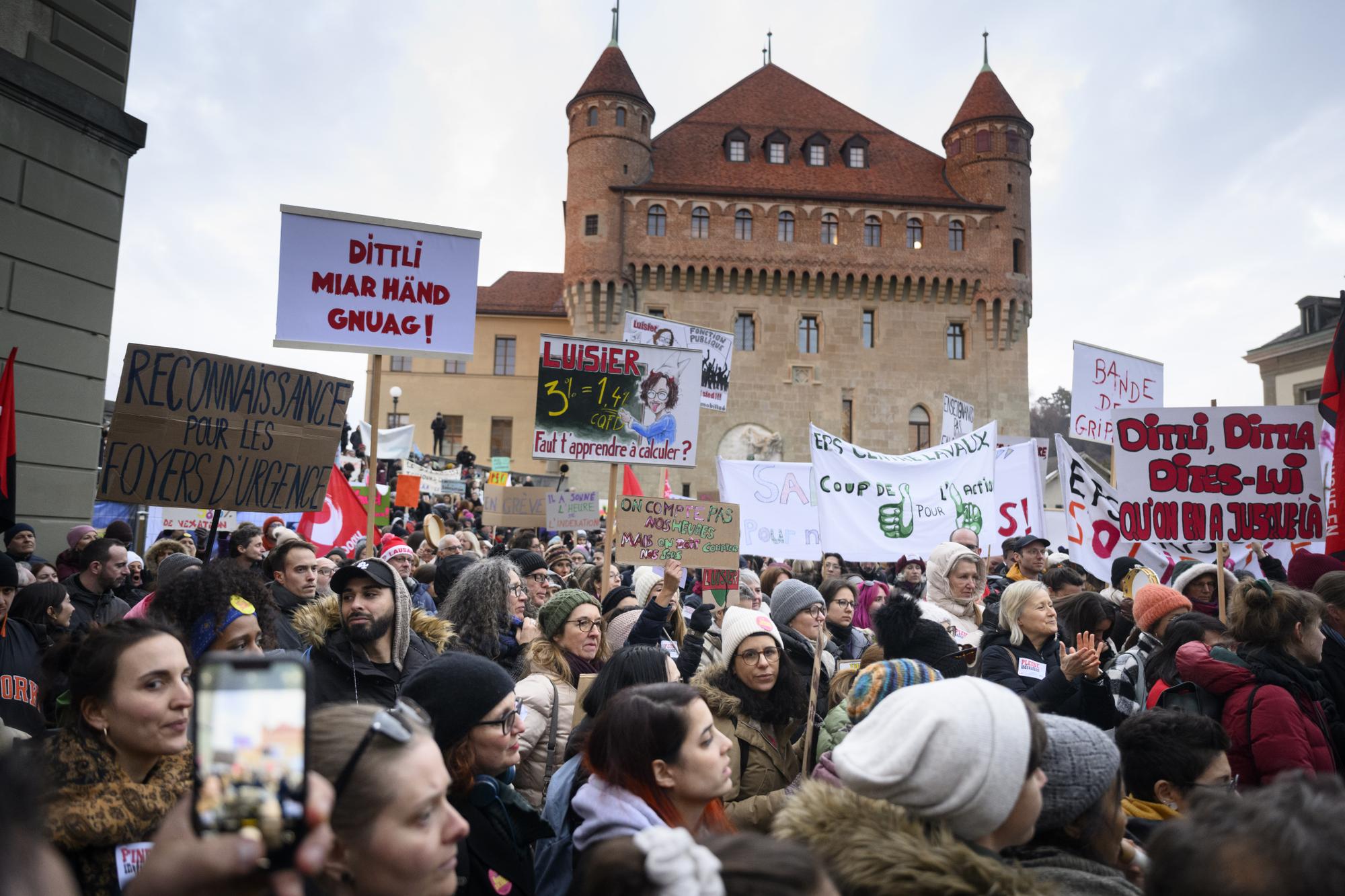 Des employes du canton de Vaud brandissent des pancartes devant le siege du gouvernement vaudois, le chateau Saint-Maire, lors d'un rassemblement pendant la journee d'actions et de greve de la fonction publique vaudoise, des salaries des secteurs publics a l'appel de leurs syndicats (FSF, SSP, SUD) ce mardi 31 janvier 2023 a Lausanne.(KEYSTONE/Laurent Gillieron)