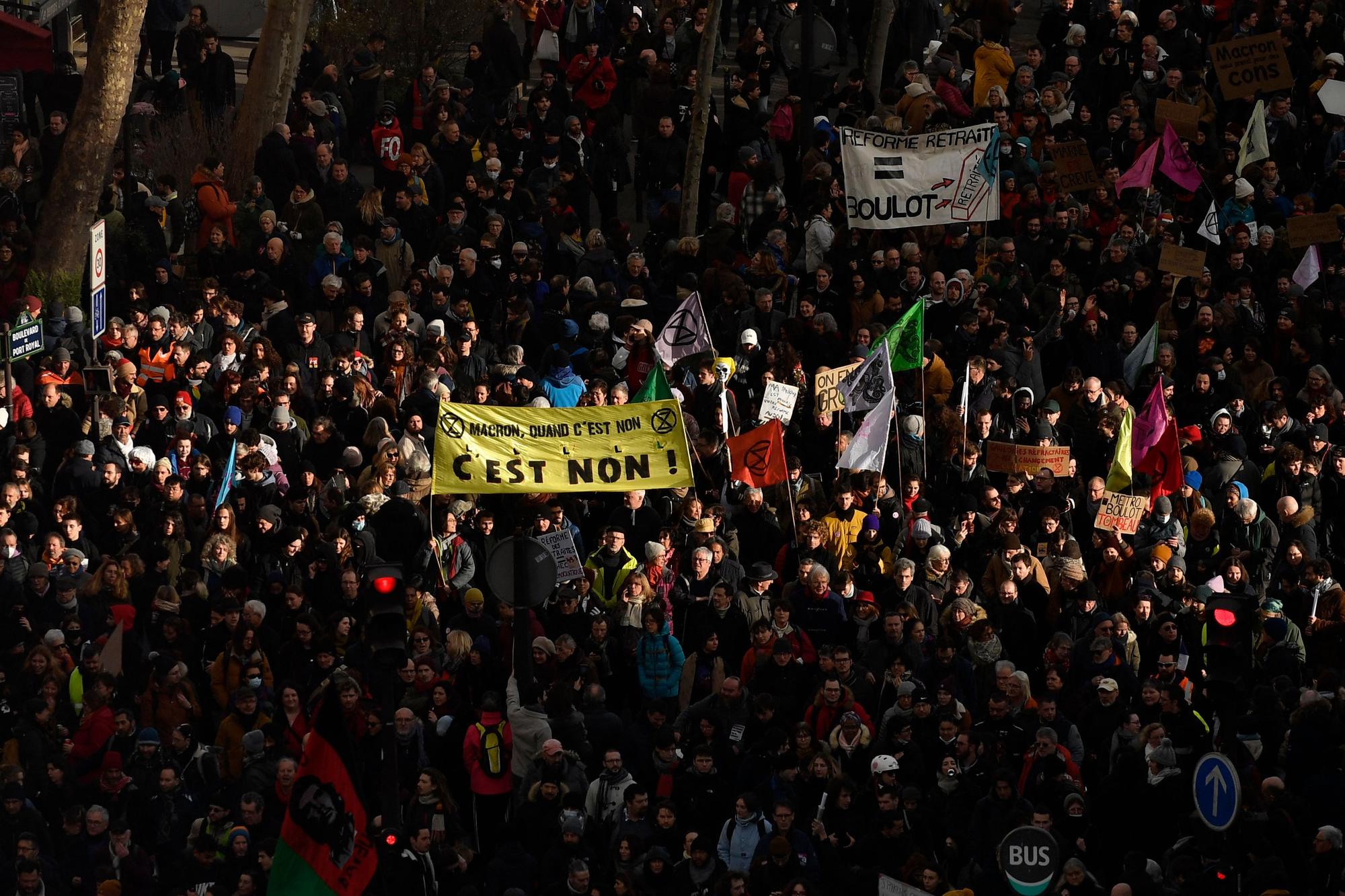 A protester holds a banner reading "Macron, No means no!" during a rally on a second day of nationwide strikes and protests over the government's proposed pension reform, in Paris on January 31, 2023. - France braces for major transport blockages, with mass strikes and protests set to hit the country for the second time in a month in objection to the planned boost of the age of retirement from 62 to 64. On January 19, some 1.1 million voiced their opposition to the proposed shake-up -- the largest protests since the last major round of pension reform in 2010. (Photo by JULIEN DE ROSA / AFP)
