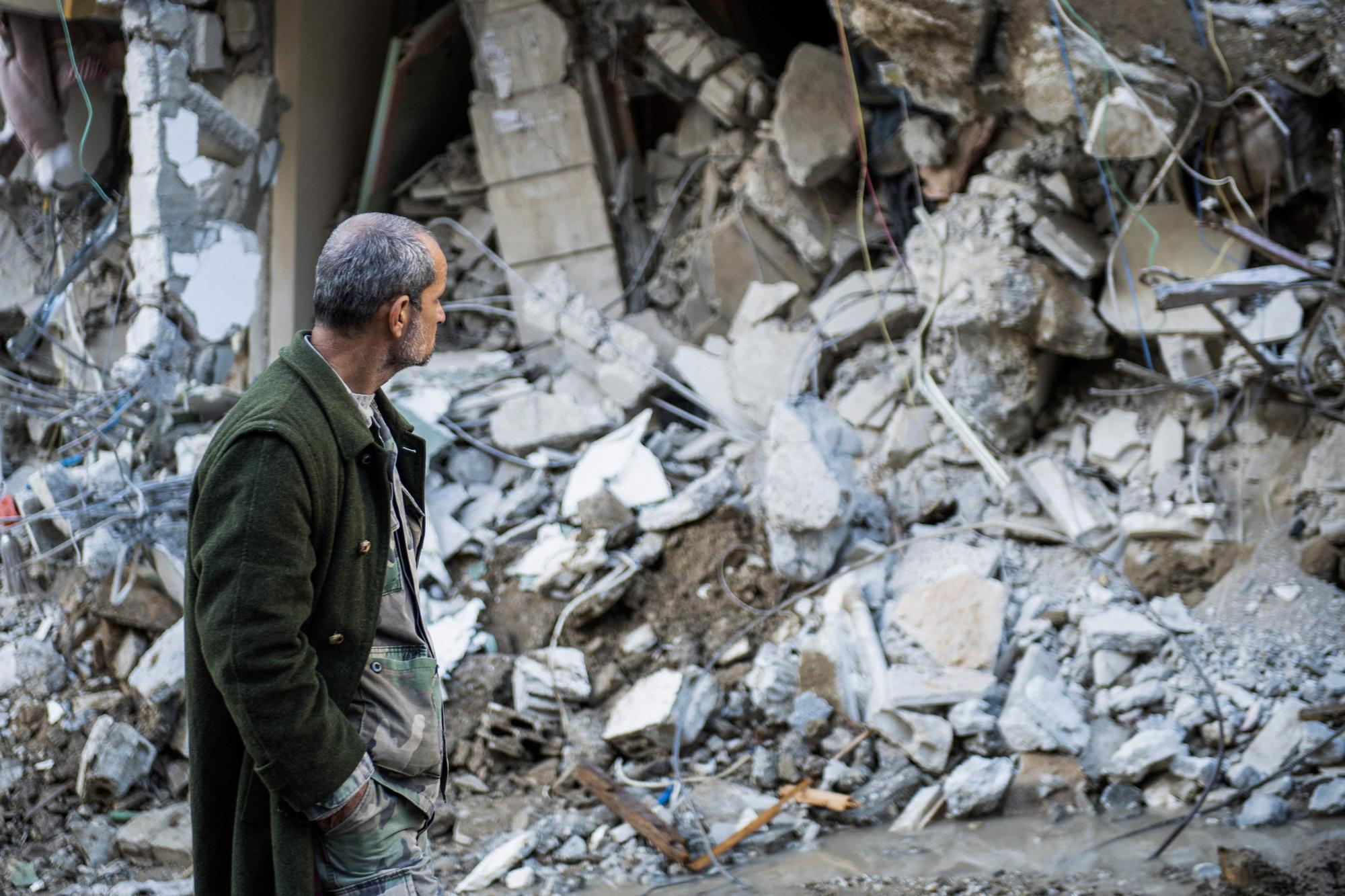 A man walks past a collapsed building in the town of Jbaleh in Syria's northwestern province of Latakia following an earthquake, on February 7, 2023. - A massive rescue effort in Turkey and Syria battled frigid weather in a race against time on February 7 to find survivors under buildings flattened by an earthquake a day earlier that killed more than 5,000 people. (Photo by AFP)