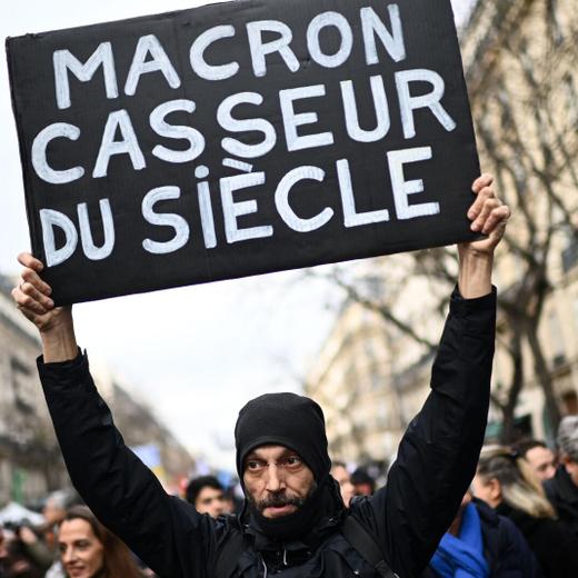 A protester holds a sign reading "Macron, destroyer of the century" during a demonstration on the fourth day of nationwide rallies organised since the start of the year, against a deeply unpopular pensions overhaul, in Paris on February 11, 2023. (Photo by Christophe ARCHAMBAULT / AFP)