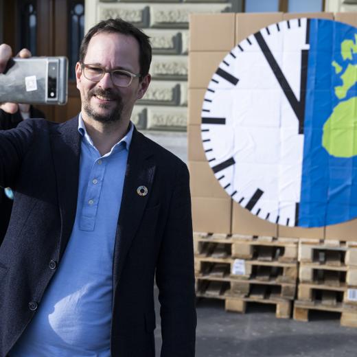 Balthasar Glaettli, Praesident Gruene Schweiz macht ein Selfie vor einer Plakatuhr die auf fuenf vor Zwoelf steht. Personen der Jungen Gruene Schweiz reichen die Umweltverantwortungsinitiative ein, am Dienstag, 21. Februar 2023, in Bern. Diese Initiative fordert, die planetaren Grenzen als Rahmen unserer Wirtschaft in die Verfassung zu schreiben. (KEYSTONE/Peter Schneider)