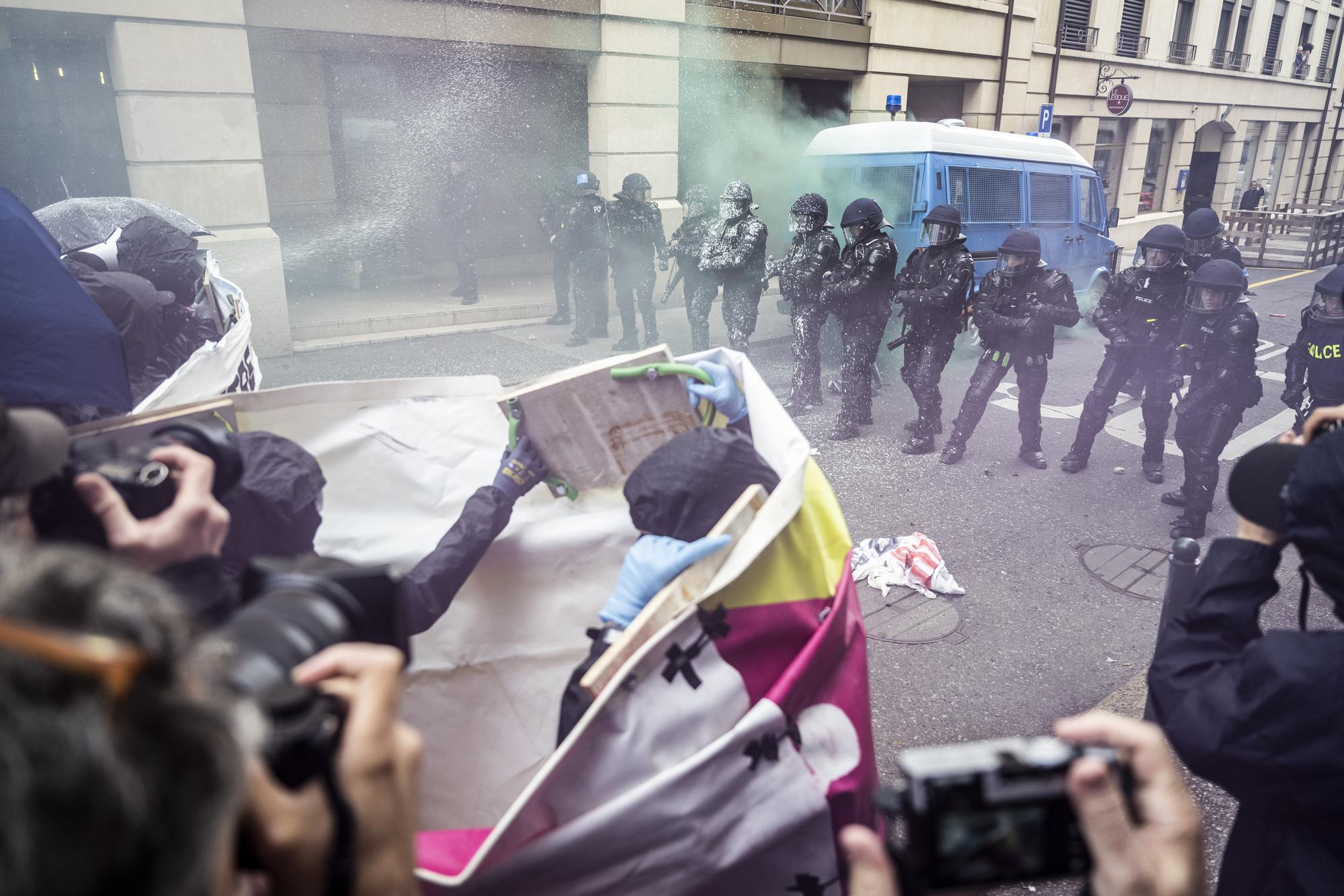 Des personnes affrontent la police genevoise, lors d'une manifestation contre la venue de l'UDC avec le slogan "tout le monde deteste l'UDC" a l'occasion de l'assemblee des delegues du parti de l' Union Democratique du Centre, UDC SVP a Geneve, ce samedi 18 mars 2023 a Geneve. (KEYSTONE/Martial Trezzini)