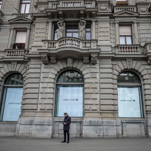 A man looks at his smartphone as he stands outside the headquarters of Credit Suisse bank in Zurich on March 20, 2023. - UBS agreed to take over Credit Suisse for $3 billion Swiss francs ($3.25 billion) in a government-brokered deal over the weekend following days of market upheaval over the health of the banking sector. (Photo by Fabrice COFFRINI / AFP)
