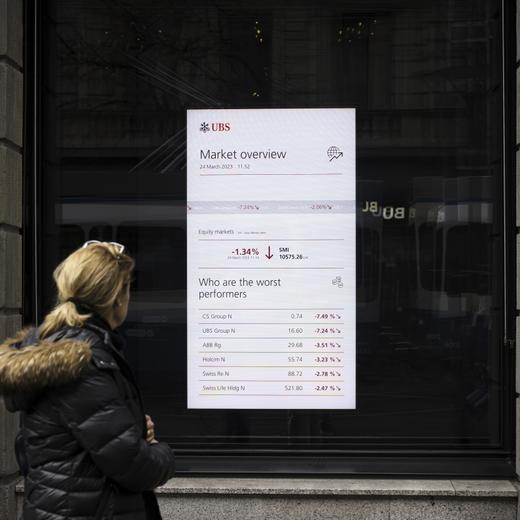 A woman looks at a market board at the headquarters of the Swiss bank UBS in Zurich, Switzerland, Friday, March 24, 2023. (Michael Buholzer/Keystone via AP)
