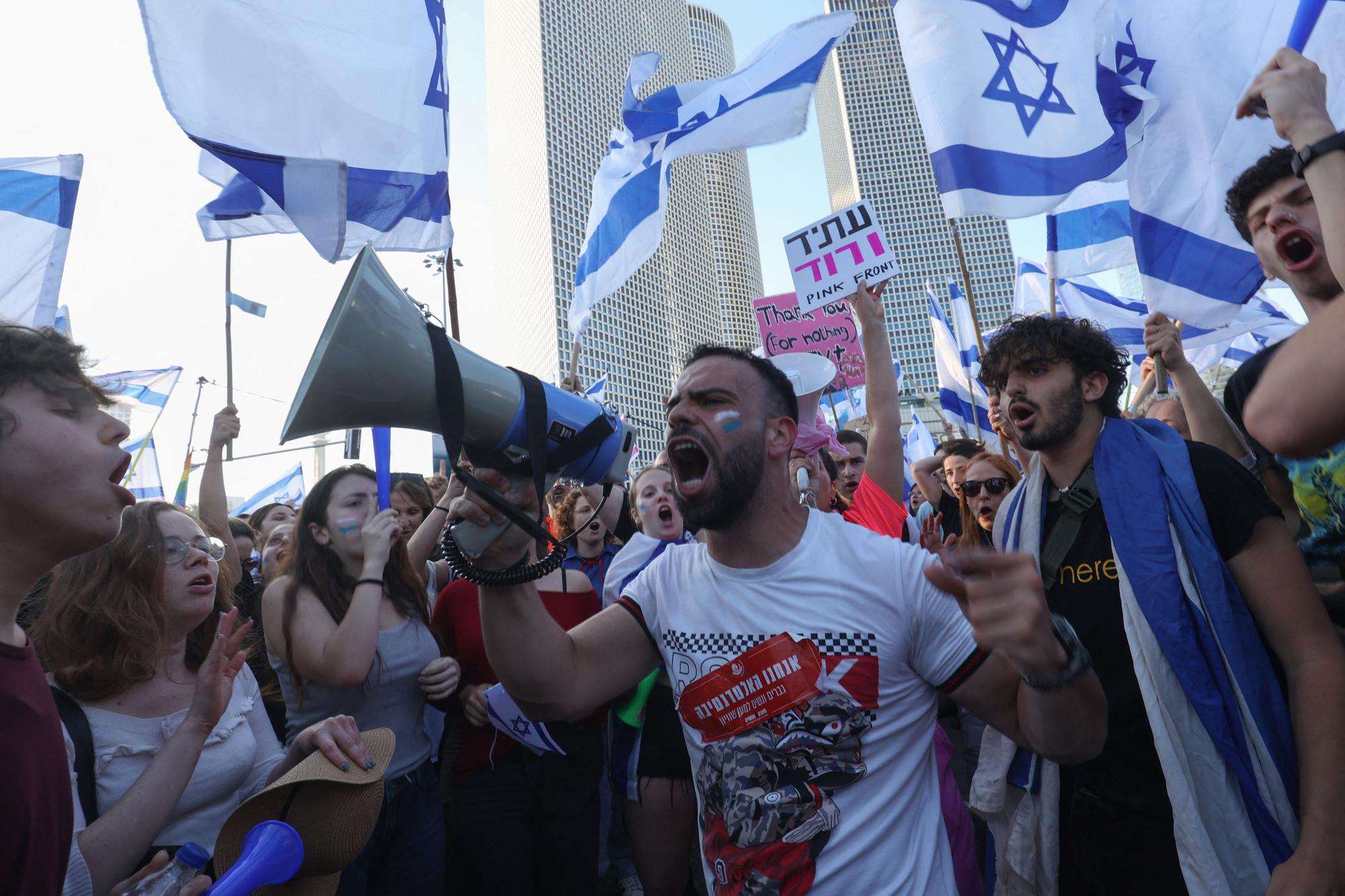 A protester uses a megaphone during a gathering in Tel Aviv on March 27, 2023, amid ongoing demonstrations and calls for a general strike against the hard-right government's controversial push to overhaul the justice system. (Photo by GIL COHEN-MAGEN / AFP)