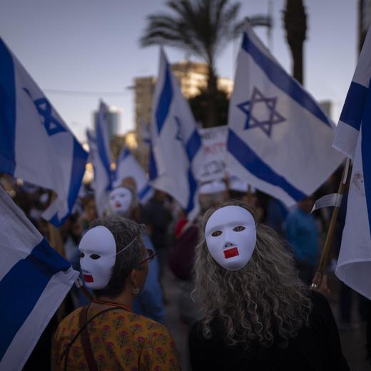 Demonstrators wear masks and wave Israeli flags during a protest against plans by Prime Minister Benjamin Netanyahu's government to overhaul the judicial system in Tel Aviv, Israel, Tuesday, March 28, 2023. Netanyahu said Monday he was freezing the plan to give time to seek a compromise with his opponents, but protesters have vowed to continue their demonstrations, saying they don't trust him. (AP Photo/Oded Balilty)