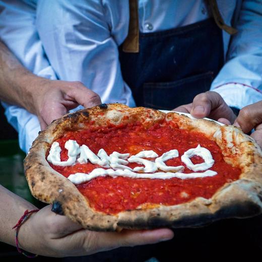 epa06373795 Neapolitan 'Pizzaiuoli' (pizza makers) celebrate UNESCO's recognition by offering slices of pizza to passers-by on the street in Naples, southern Italy, 07 December 2017. UNESCO said that the art of the Neapolitan 'Pizzaiuolo' (pizza maker) has been put on its Intangible Cultural Heritage list. EPA/CESARE ABBATE