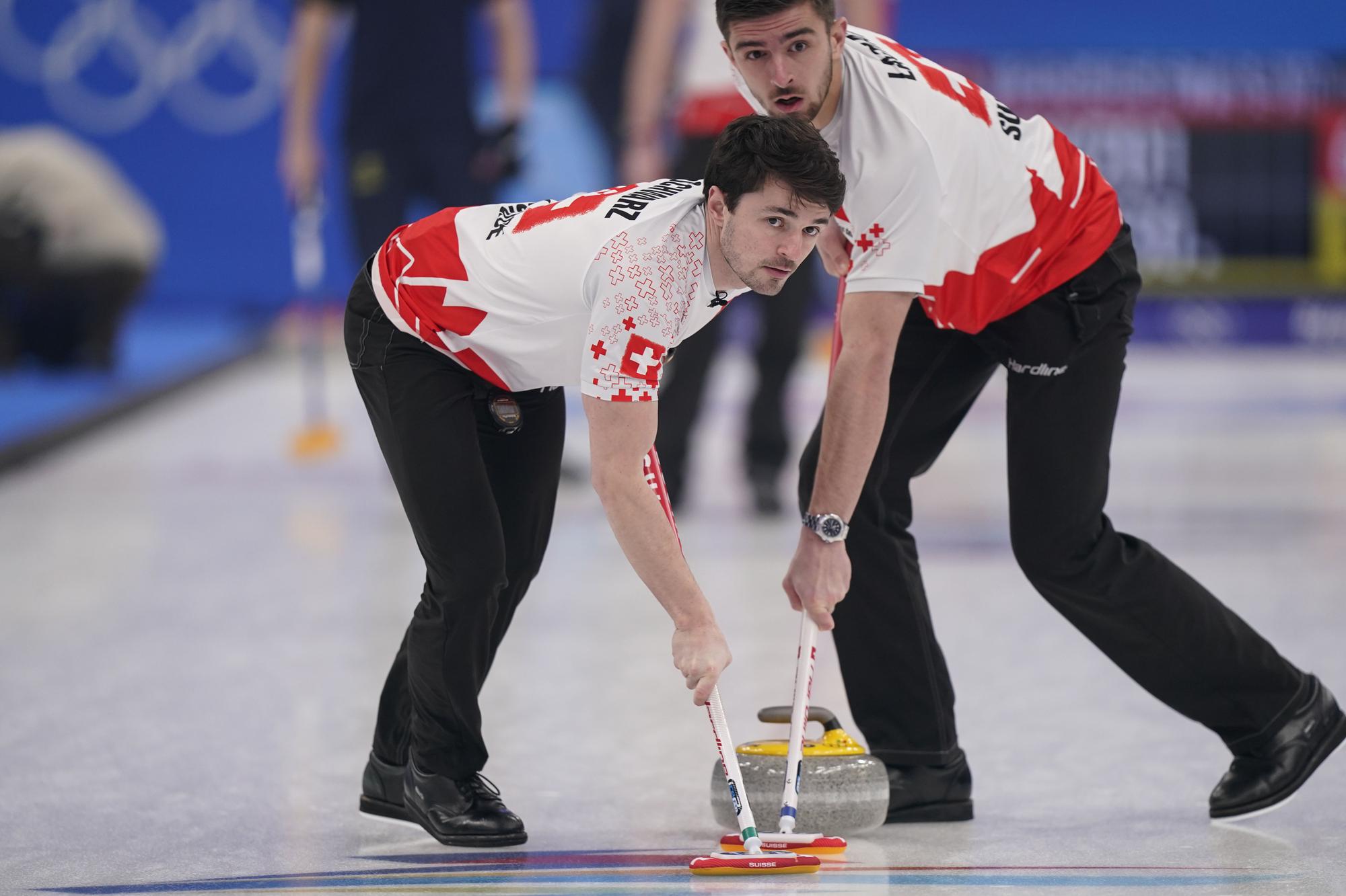 Switzerland's Benoit Schwarz, left, and Switzerland's Pablo Lachat sweep during a men's curling match against Sweden at the Beijing Winter Olympics Thursday, Feb. 17, 2022, in Beijing. (AP Photo/Brynn Anderson)