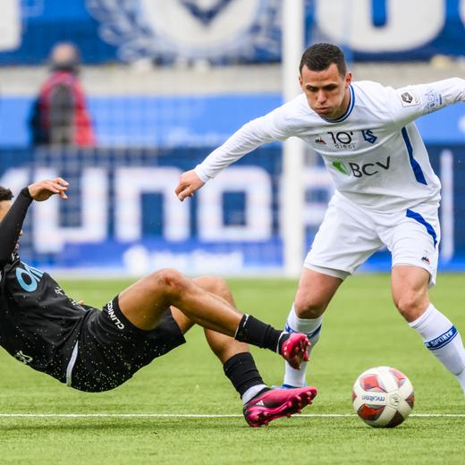 Le milieu yverdonnois Mauro Rodrigues, gauche, lutte pour le ballon avec le milieu lausannois Stjepan Kukuruzovic, droite, lors de la rencontre de football de Challenge League entre FC Lausanne-Sport et Yverdon Sport FC le dimanche 2 avril 2023 au sade de la Tuiliere a Lausanne. (KEYSTONE/Jean-Christophe Bott)
