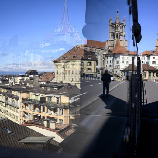 Des personnes marchent devant la a Cathedrale de Lausanne qui se reflete dans une vitre du Pont Bessiere ce lundi 3 avril 2023 a Lausanne. Les comptes 2022 de la Ville de Lausanne affichent un deficit de 10,8 millions de francs. Le resultat s'affiche dans la lignee des annees precedentes, mais en nette amelioration par rapport au deficit de 66 millions qui avait ete budgete.(KEYSTONE/Laurent Gillieron)
