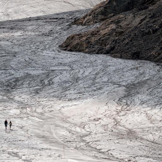 A couple hold their hands while walking on the melting Tsanfleuron Glacier above Les Diablerets on August 6, 2022. - Following several heatwaves blamed by scientists on climate change, Switzerland is seeing its alpine glaciers melting at an increasingly rapid rate. (Photo by Fabrice COFFRINI / AFP)