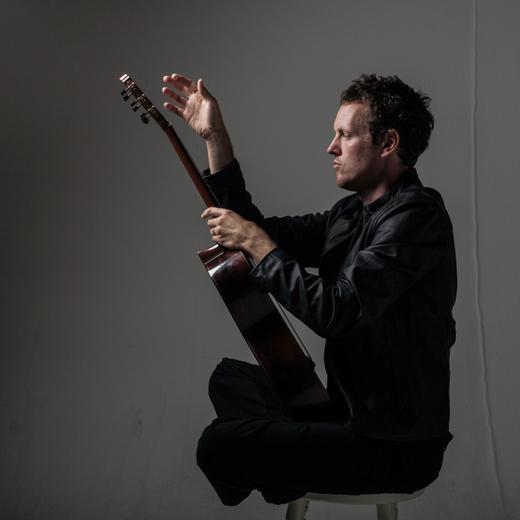 Derek Grripper, face à sa guitare qu'il tient comme une kora.