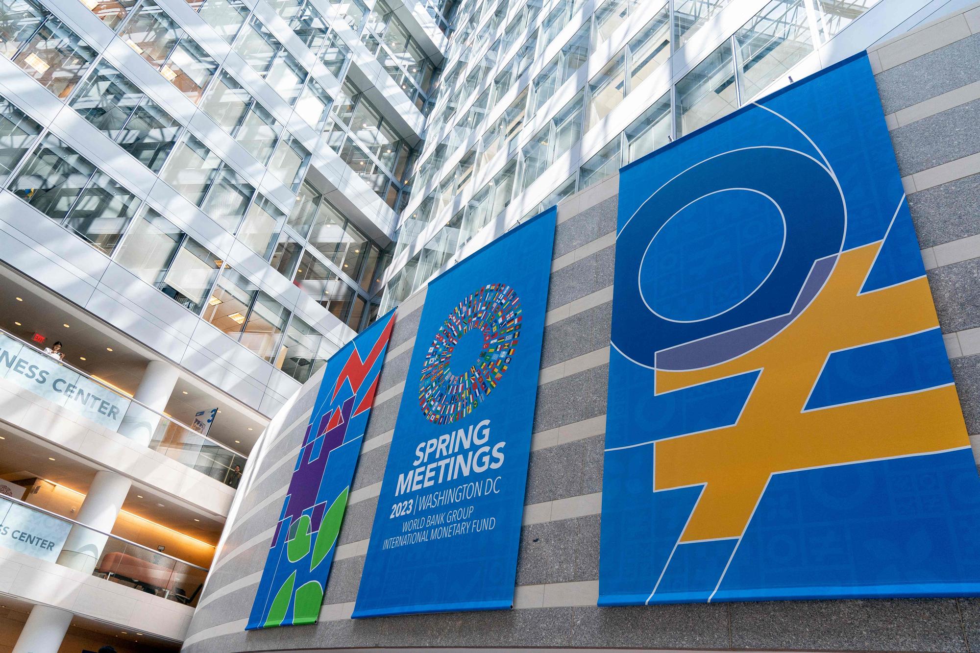 Spring Meetings signs are displayed in the International Monetary Fund (IMF) headquarters in Washington, DC, on April 12, 2023. (Photo by Stefani Reynolds / AFP)