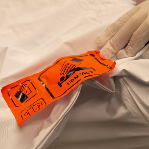 Un employe des pompes funebres va prepare un corps dans le centre funeraire du cimetiere des Rois, ce vendredi 20 novembre 2020 a Geneve. Le service des pompes funebres de la Ville de Geneve ne sait plus ou donner de la tete a cause de la crise sanitaire. Les places dans les chambres froides des cimetieres de Saint-Georges et des Rois sont toutes occupees et des corps ont du etre transferes a la morgue des Hopitaux universitaires de Geneve (HUG). (KEYSTONE/Salvatore Di Nolfi)