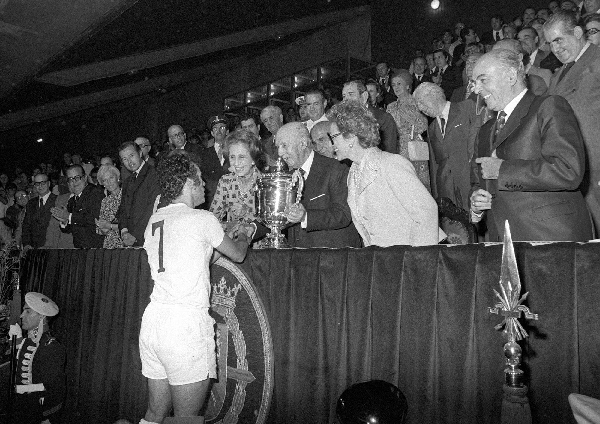 FINAL COPA DEL GENERALÍSIMO DE FUTBOL: Madrid, 5-7-1975.- El jefe del Estado, Francisco Franco, felicita al capitán del Real Madrid, Amancio, tras proclamarse campeón de la Copa del Generalísimo al derrotar al Atlético de Madrid en la final en la tanda de penalties. En el palco también se encuentran Carmen Polo, el duque de Cádiz, el secretario general del Movimiento, José Solis Ruiz. (KEYSTONE/EFE/Str)
