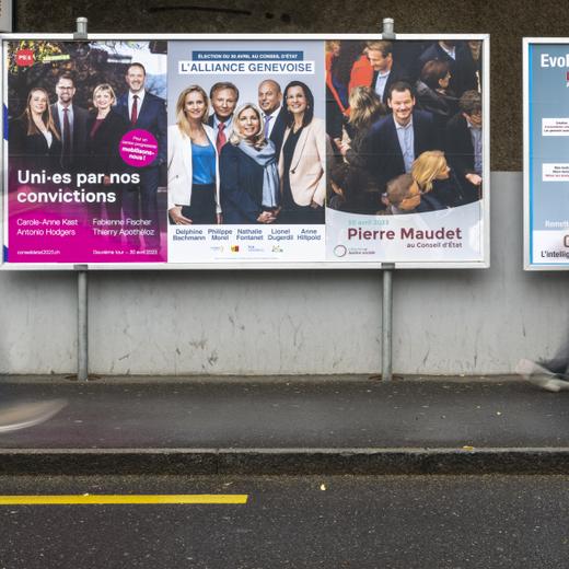 Deux personnes passent devant les affiches electorales du deuxieme tour de l'election du Conseil d'Etat, l'affiche du parti Socialiste et les Verts avec les candidats, Carole-Anne Kast, Antonio Hodgers, Fabienne Fischer, Thierry Apotheloz, l'affiche de l'alliance genevoise avec les candidats, Delphine Bachmann - Le Centre, Philippe Morel - MCG, Nathalie Fontanet - PLR, Lionel Dugerdil - UDC et Anne Hiltpold - PLR et l'affiche de Libertes et Justice sociale Pierre Maudet, ce jeudi 20 avril 2023 a Geneve. Les citoyens genevois voteront pour l'election du second tour de l'election du Conseil d'Etat du dimanche 30 avril 2023. (KEYSTONE/Martial Trezzini)
