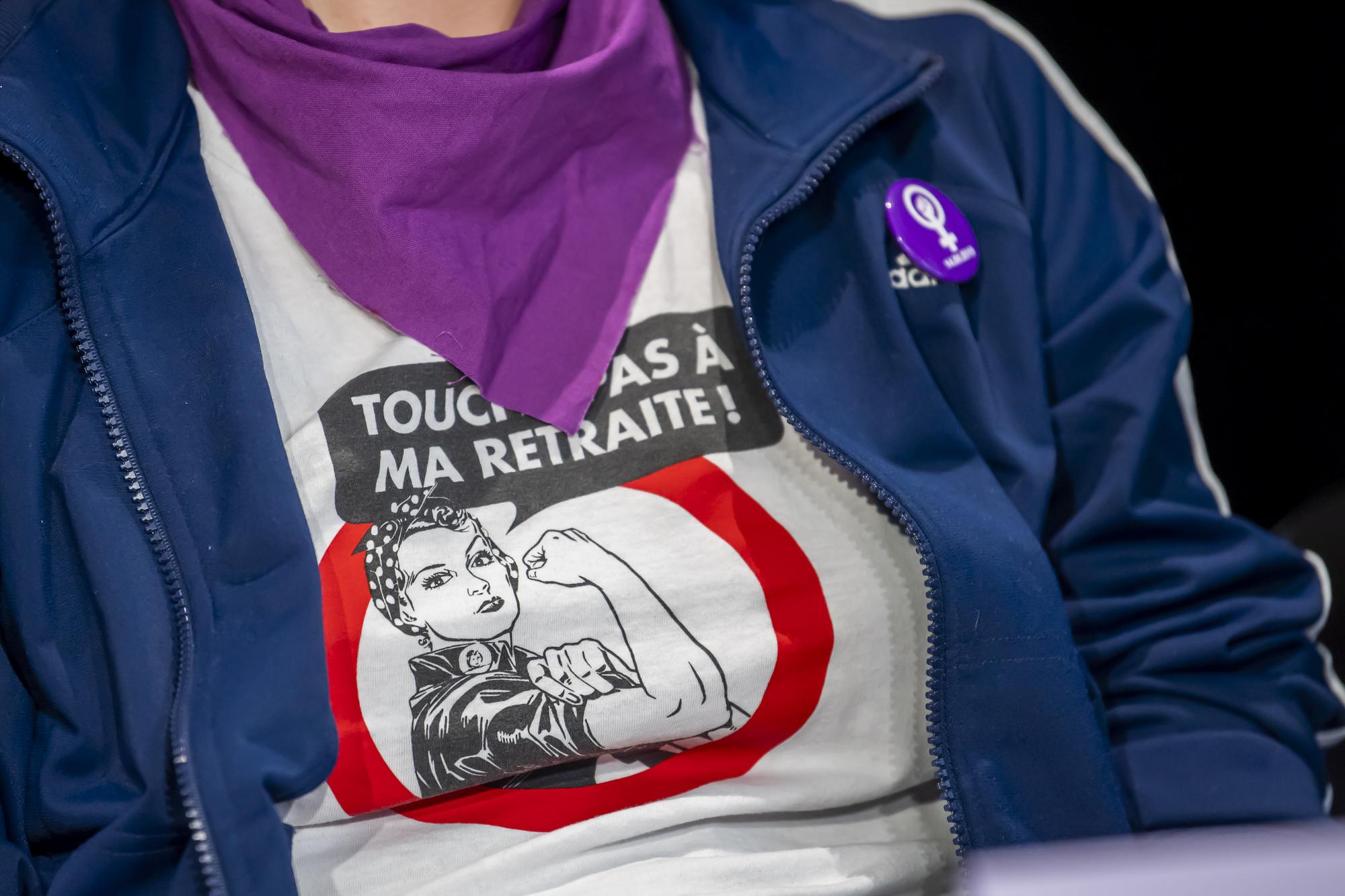 Un dessin d'une femme qui fait une bras d'honneur avec le slogan, "Touche pas a ma retraite !" Est photographie sur une membres du Collectif Genevois pour la greve feministe, lors de la presentation du programme de la journee Internationale de lutte pour les droits des Femmes qui aura lieu le 8 mars, lors d'une conference de presse, ce mercredi 3 mars 2021 a Geneve. (KEYSTONE/Martial Trezzini)