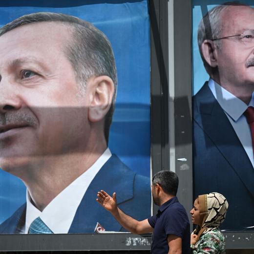 A couple walks past billboards with the portrait of Turkish President Recep Tayyip Erdogan (L) and with the portrait of Republican People's Party (CHP) leader and presidential candidate, Kemal Kilicdaroglu (R) in Sanliurfa, south-eastern Turkey on April 28, 2023. (Photo by OZAN KOSE / AFP)