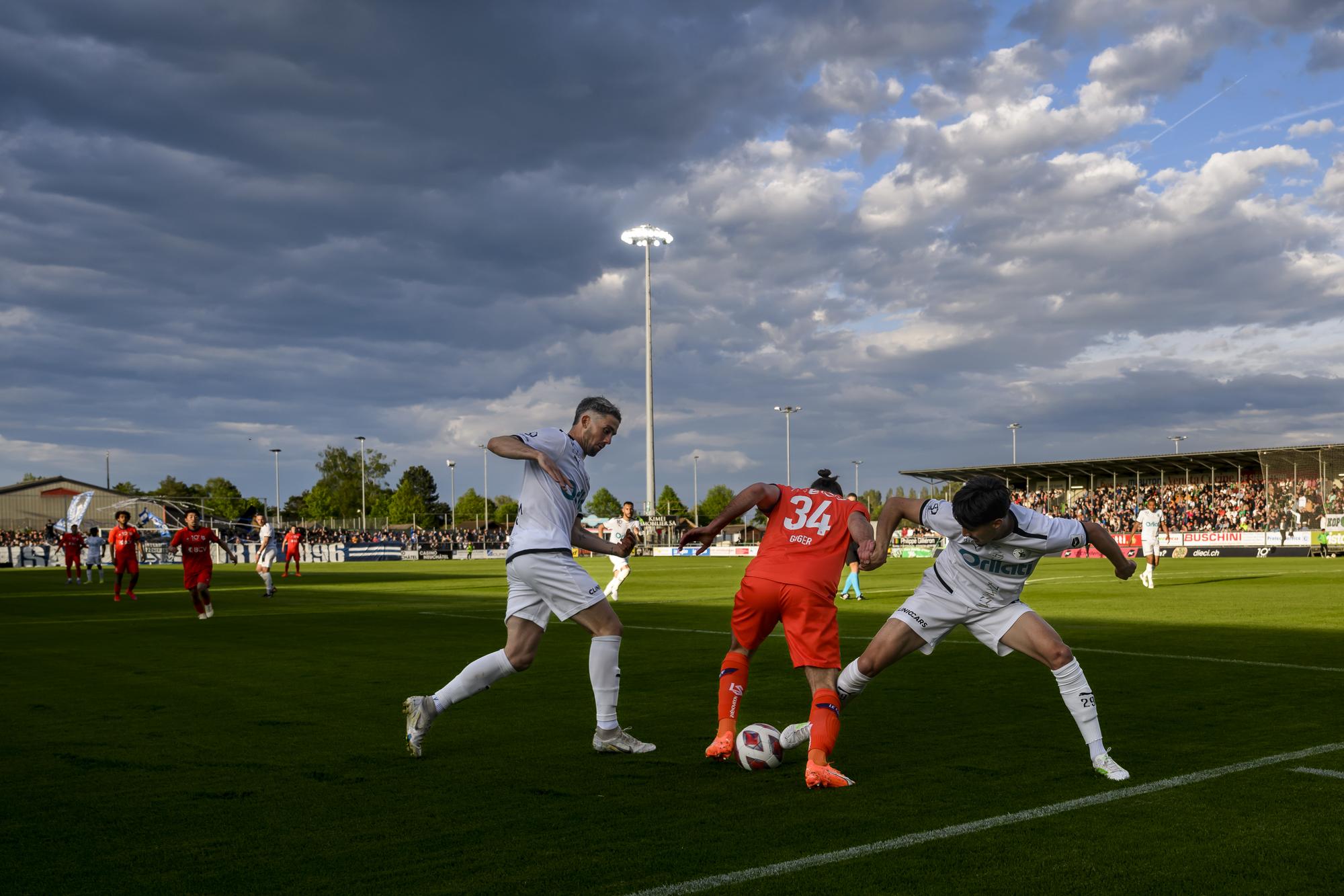 Le defenseur lausannois Raoul Giger, centre, lutte pour le ballon avec le defenseur yverdonnois William Le Pogam, gauche, et l'attaquant yverdonnois Theo Berdayes, droite, lors de la rencontre de football de Challenge League entre Yverdon Sport FC et FC Lausanne-Sport le vendredi 5 mai 2023 au stade Municipal a Yverdon. (KEYSTONE/Jean-Christophe Bott)
