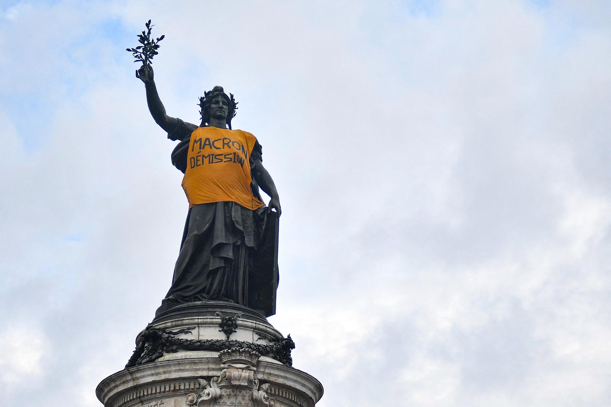 A makeshift yellow vest bearing the slogan "Macron resign" adorns the Monument a la Republique, on Paris' Place de la Republique during a demonstration on May Day (Labour Day), to mark the international day of the workers, more than a month after the government pushed an unpopular pensions reform act through parliament, in Paris, on May 1, 2023. - Opposition parties and trade unions have urged protesters to maintain their three-month campaign against the law that will hike the retirement age to 64 from 62. (Photo by JULIEN DE ROSA / AFP)