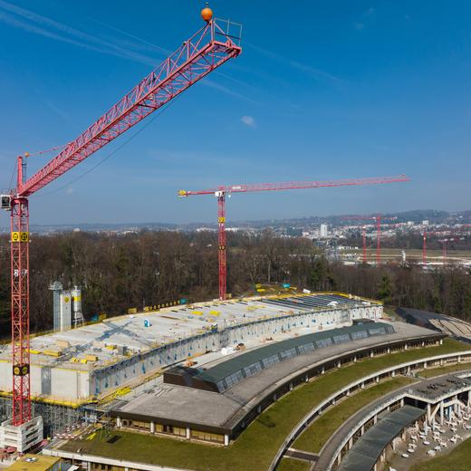 Extension de l'Unithèque, fin du coffrage des poutres du toit, pose des vitrages. Grues. Mars 2023. Photographié à l'aide d'un drone.
