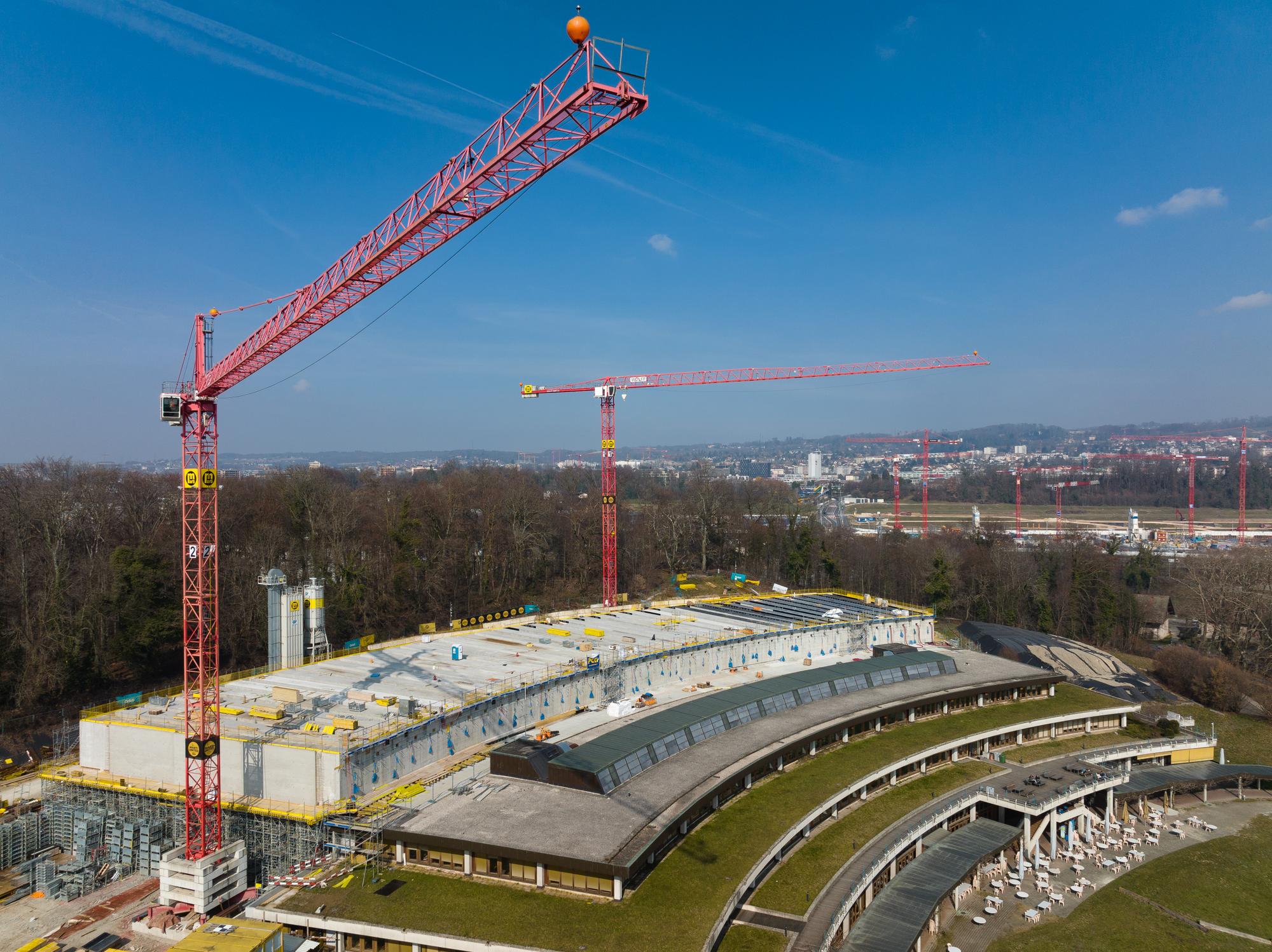 Extension de l'Unithèque, fin du coffrage des poutres du toit, pose des vitrages. Grues. Mars 2023. Photographié à l'aide d'un drone.