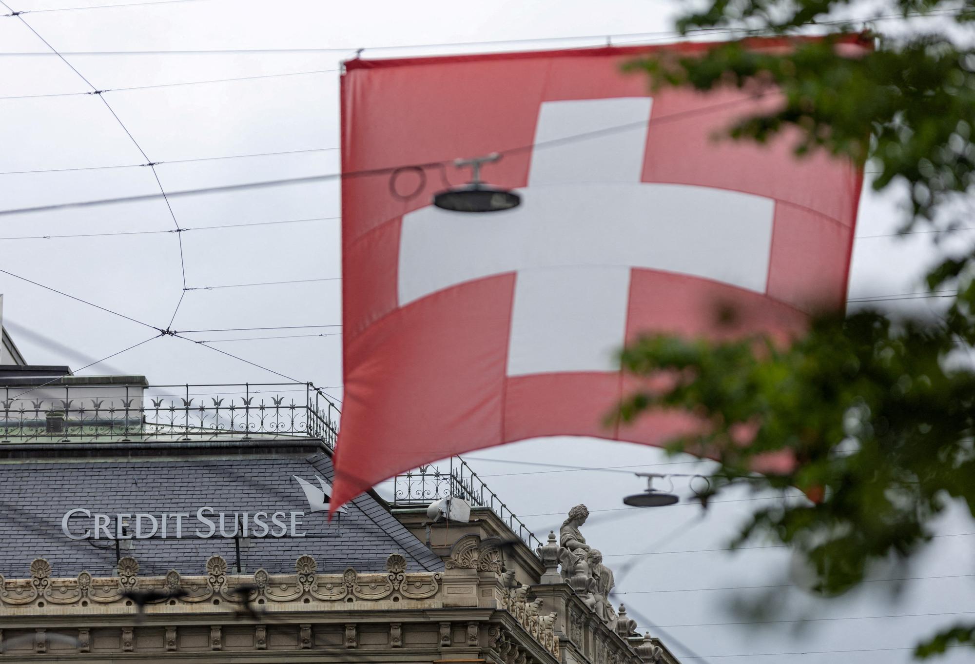 FILE PHOTO: A Swiss flag is seen in front of a logo of Swiss bank Credit Suisse in Zurich, Switzerland May 10, 2023. REUTERS/Denis Balibouse/File Photo