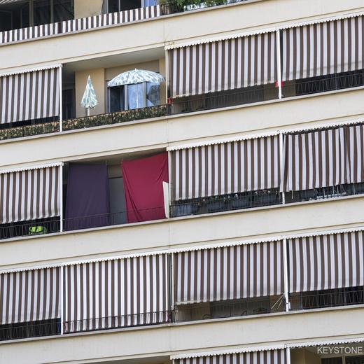 Une facade d?un immeuble est photographiee avec des parasols de jardin et les stores en toile pour balcon qui sont fermes afin d?assurer au mieux la fraicheur dans les appartements en cette periode de canicule, ce mercredi 20 juillet 2022 a Geneve. (KEYSTONE/Martial Trezzini)
