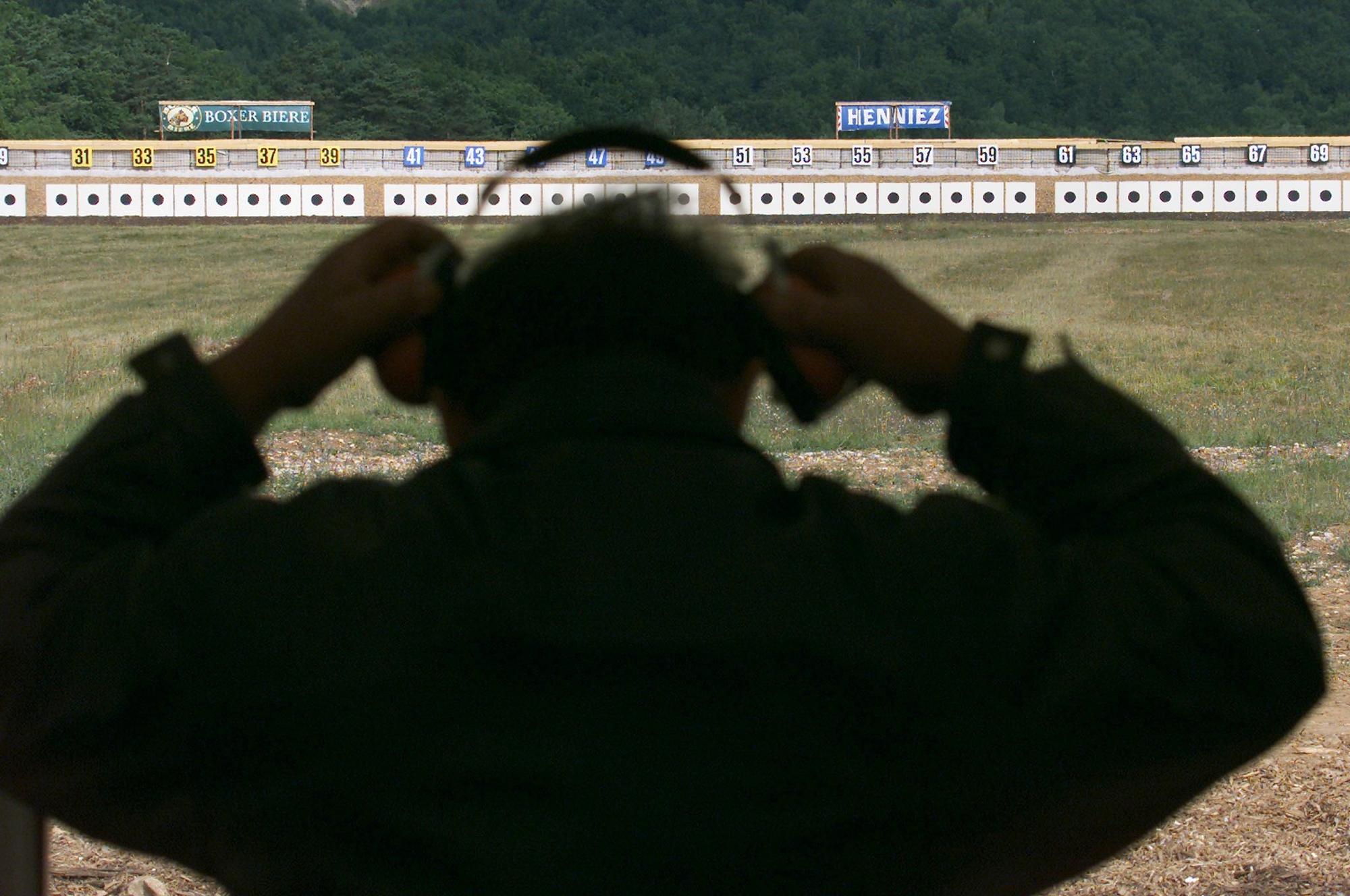 Un tireur ajuste son casque de protection acoustique avant de tirer sur l'une des 300 cibles, lors de la journee d'ouverture du Tir Federal 2000 a Biere VD, ce vendredi 23 juin 2000. Du 23 juin au 16 juillet et cinq ans apres la derniere edition de Thoune, la Place d'armes de Biere accueille le Tir Federal. Un evenement pour la Suisse romande, qui n'a pas accueilli cette manifestation depuis 1954. Quelques 56 000 tireurs rivaliserons d'adresse, durant les trois semaines que dureront la manifestation. Au total, ils tireront 3,5 millions de cartouches, soit 13 tonnes de plomb et autant d'acier. (KEYSTONE/Fabrice Coffrini) ===ELECTRONIC IMAGE===