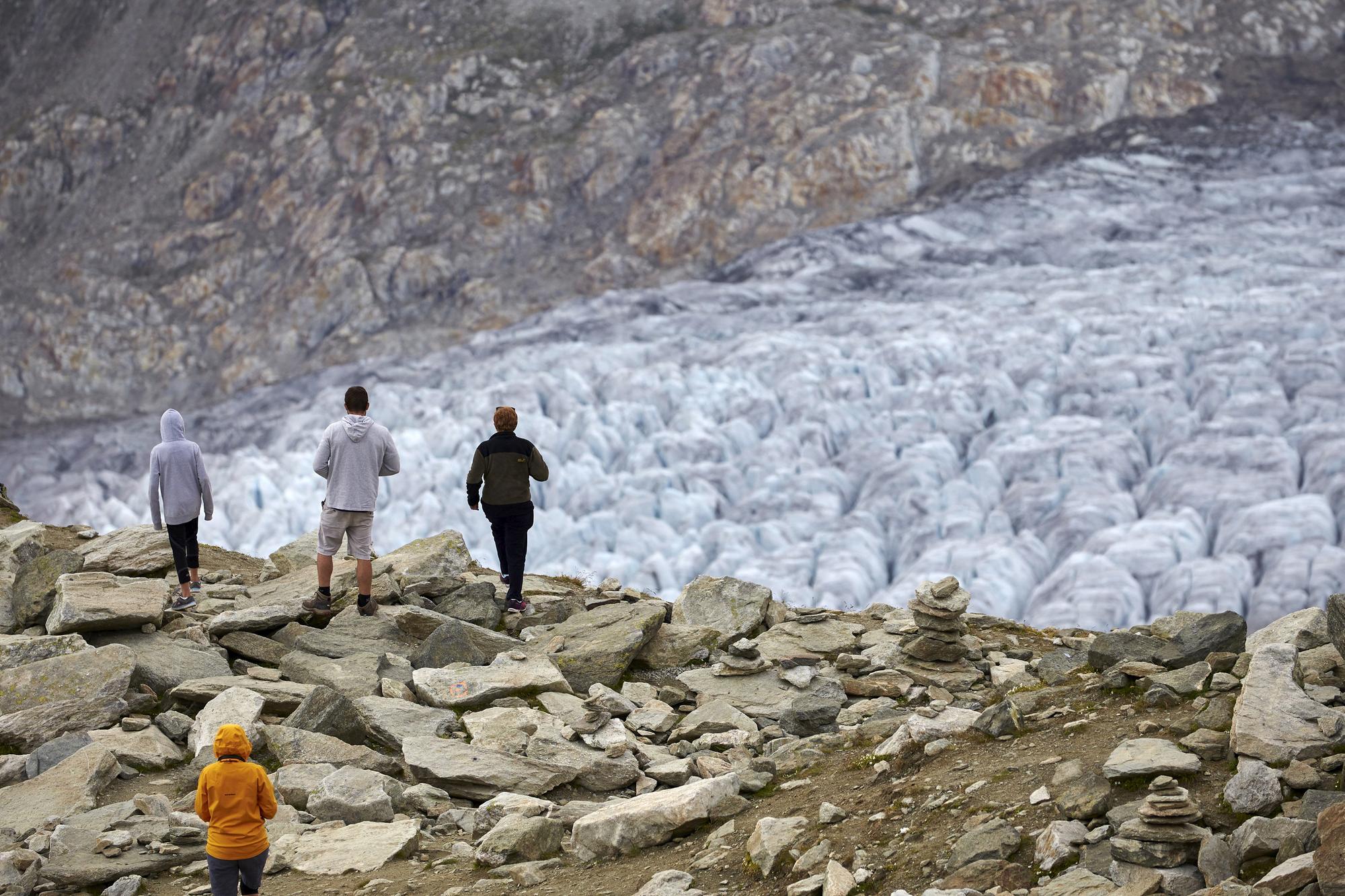 Hikers walk on the Aletsch Glacier near the Eggishorn in Fiesch, Switzerland, August 22, 2015. One of Europe's biggest glaciers, the Great Aletsch coils 23 km (14 miles) through the Swiss Alps - and yet this mighty river of ice could almost vanish in the lifetimes of people born today because of climate change. The glacier, 900 metres (2,950 feet) thick at one point, has retreated about 3 km (1.9 miles) since 1870 and that pace is quickening. REUTERS/Denis Balibouse??PICTURE 12 OF 31 FOR WIDER IMAGE STORY "EARTHPRINTS: ALETSCH GLACIER". SEARCH "EARTHPRINTS ALETSCH" FOR ALL IMAGES. - RTS4K1I