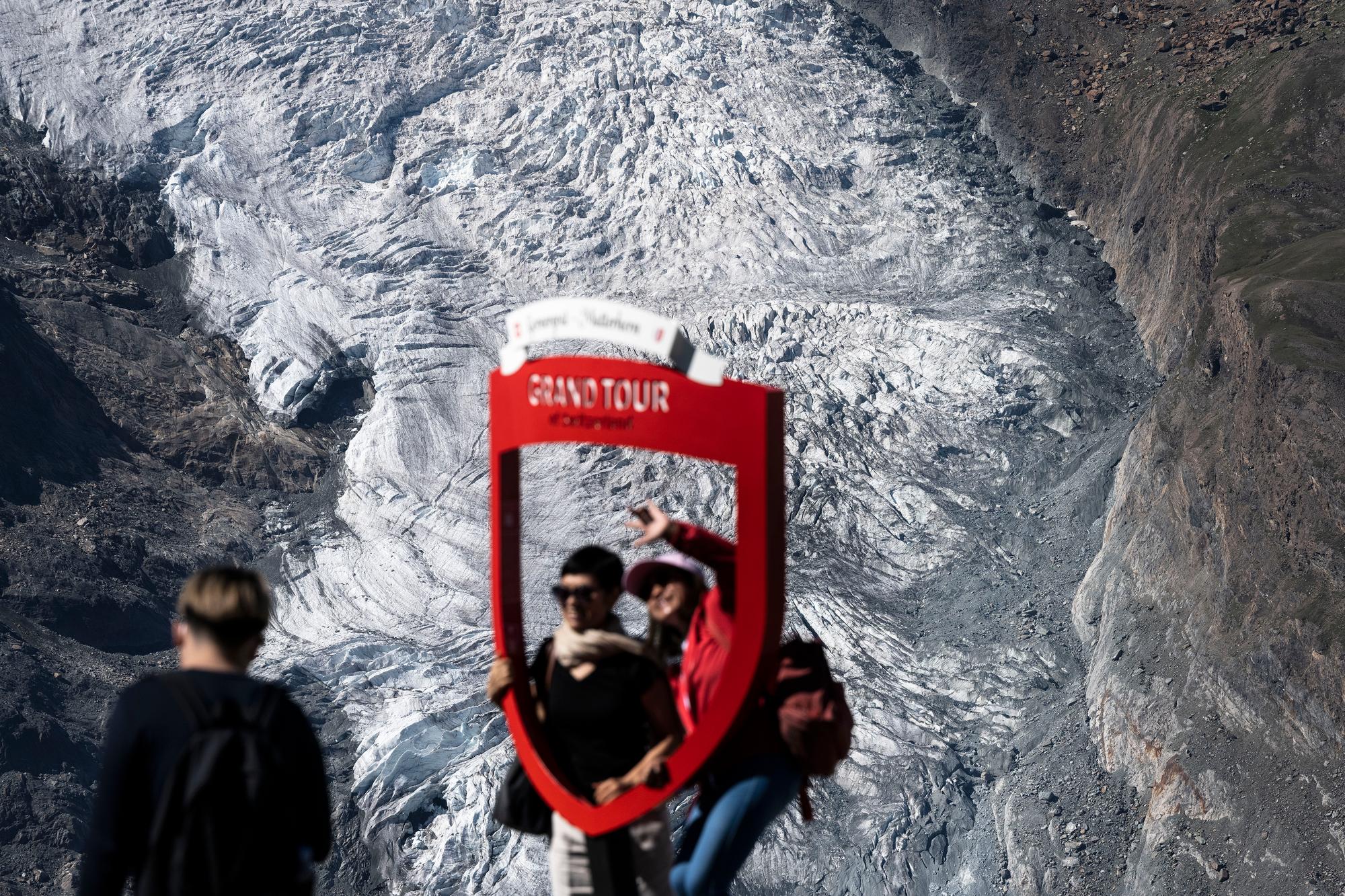 Touristen fotografieren sich im Grand Tour Schild beim Bahnhof auf dem Gornergrat, fotografiert am Montag, 25. Juli 2022 oberhalb von Zermatt. im Hintergrund sind Teile eines Gletschers zu sehen. (KEYSTONE/Christian Beutler)
