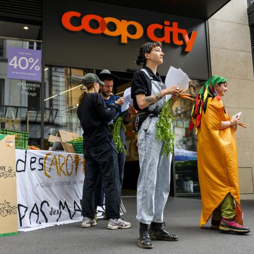 Des militants du collectif "Grondements des terres", tiennent un stand devant l'entree du magasin Coop city, contre les marges des entreprises de la grande distribution Coop et Migros le samedi 10 juin 2023 a Lausanne. (KEYSTONE/Jean-Christophe Bott)
