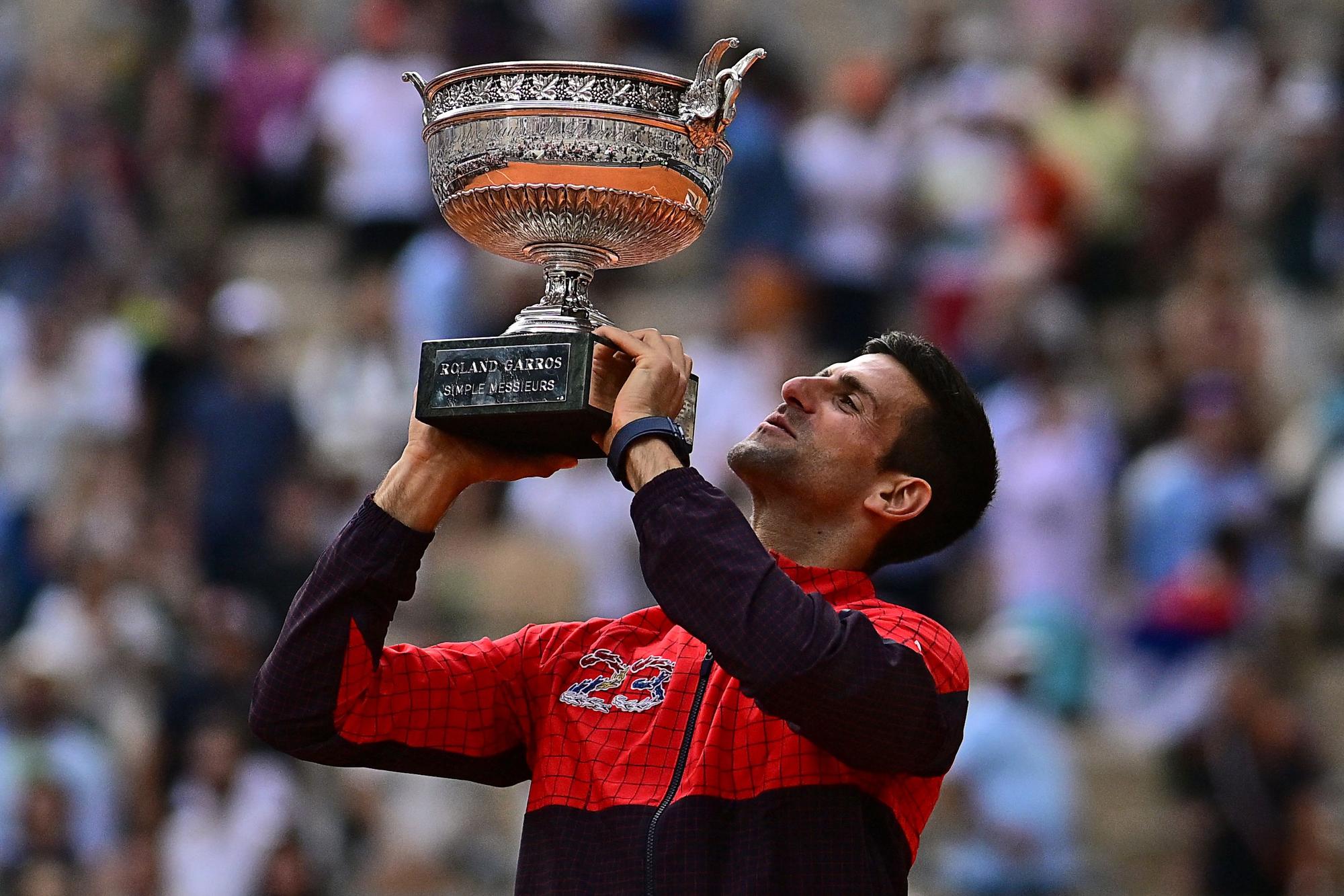 Serbia's Novak Djokovic raises his trophy as he celebrates his victory over Norway's Casper Ruud during their men's singles final match on day fifteen of the Roland-Garros Open tennis tournament at the Court Philippe-Chatrier in Paris on June 11, 2023. (Photo by JULIEN DE ROSA / AFP)