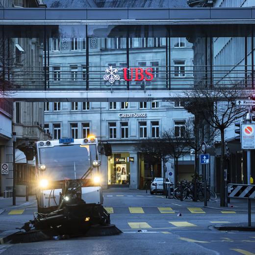 A cleaning vehicle collects garbage past logos of the Swiss banks Credit Suisse and UBS in Zurich, Switzerland on Sunday March 19, 2023. (KEYSTONE/Michael Buholzer).