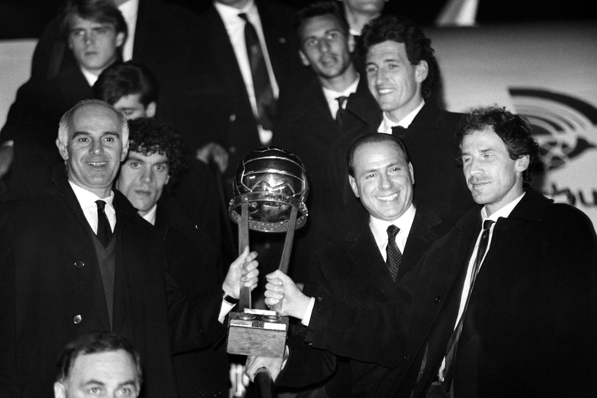 FILE - AC Milan former coach Arrigo Sacchi, left, AC Milan president Silvio Berlusconi, second from right, and Franco Baresi, right, show the Intercontinental Cup as they arrive at the Milan Linate airport on Dec. 1990. From his grand entrance by helicopter after buying AC Milan to empowering Monza up to Serie A for the first time in its history, Silvio Berlusconi dominated Italian soccer for decades just like he commanded the show in Italian politics. Berlusconi, a former three-time Italian premier, died Monday, according to his television network. He was 86. (AP Photo/Luca Bruno, File)