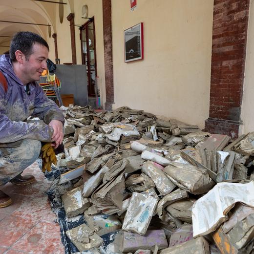 epa10638970 A man looks on books damaged following the flood that is affecting Emilia Romagna, in Faenza, Italy, 19 May 2023. Italy's northeastern region and parts of the Adriatic coast remain on red alert as the danger of landslides remains high. The death toll from this week's deadly flooding in Emilia Romagna has climbed to 14. EPA/PASQUALE BOVE