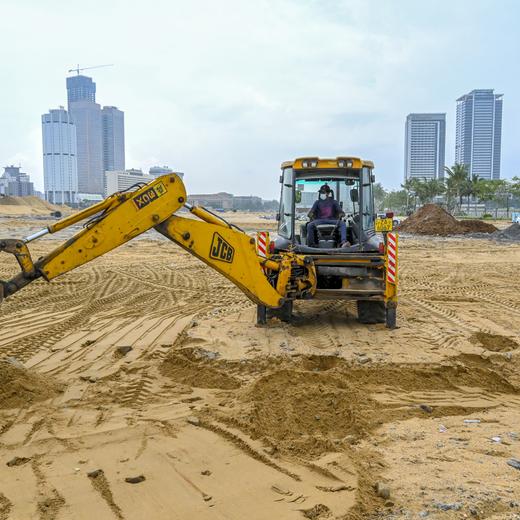 A worker uses an excavator at a construction site on reclaimed land as part of the Chinese-funded project for Port City, in Colombo on October 28, 2021. (Photo by ISHARA S. KODIKARA / AFP)
