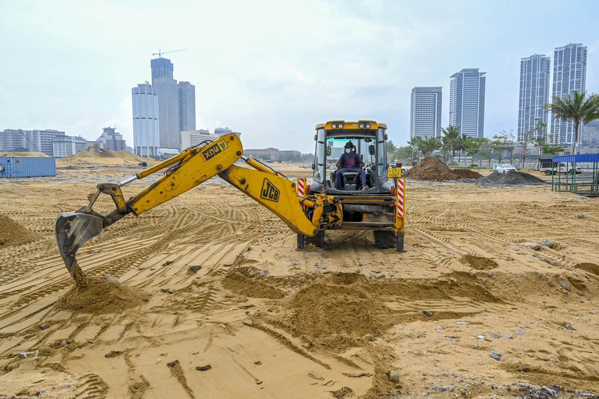A worker uses an excavator at a construction site on reclaimed land as part of the Chinese-funded project for Port City, in Colombo on October 28, 2021. (Photo by ISHARA S. KODIKARA / AFP)