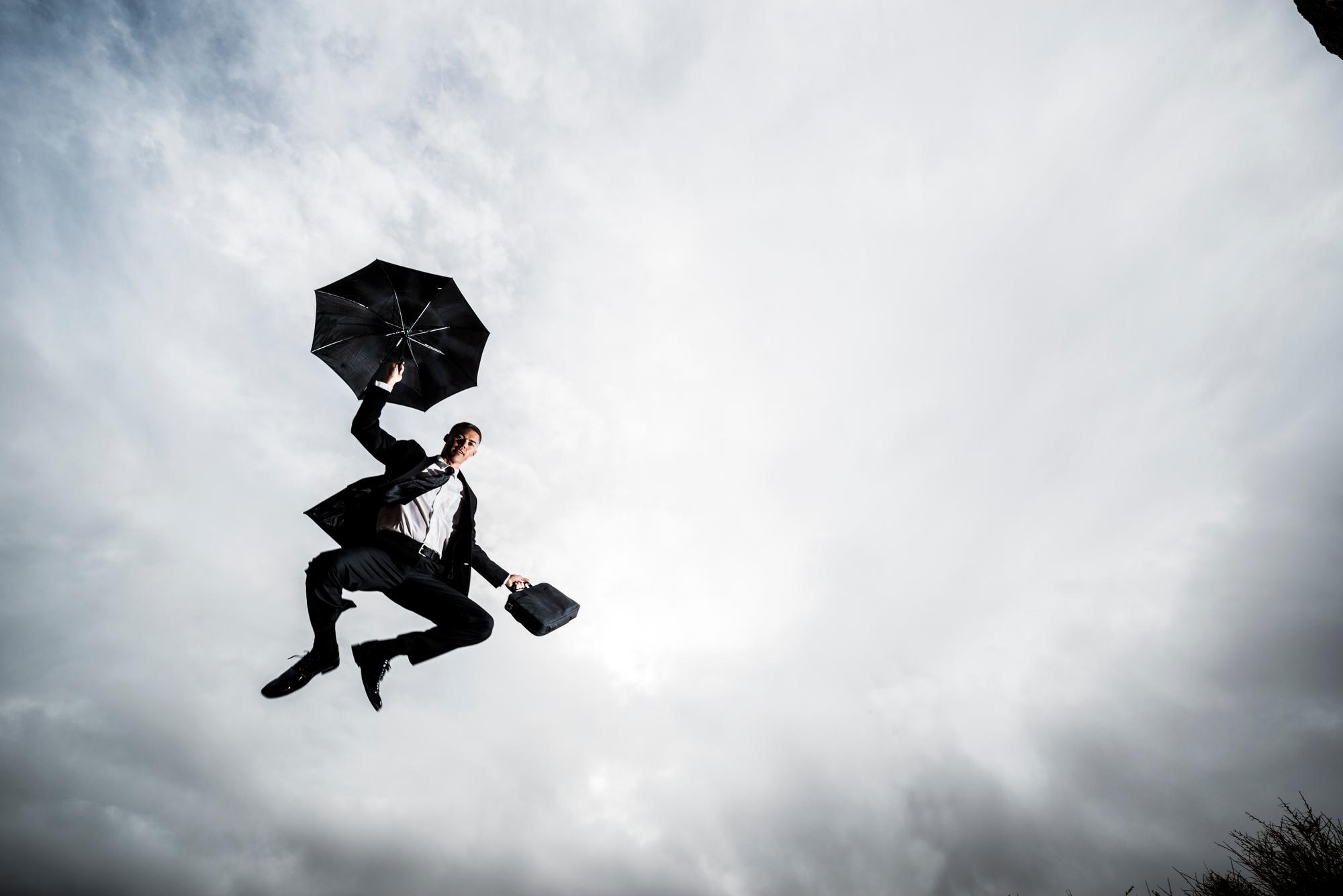 a business man landing with his umbrella
