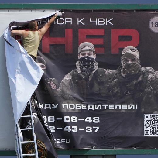 A man takes down a poster reading "Join us at Wagner", which is associated with the owner of the Wagner private military contractor, Yevgeny Prigozhin, is seen above a highway on the outskirts of St. Petersburg, Russia, Saturday, June 24, 2023. Russia's security services have responded to mercenary chief Prigozhin's declaration of an armed rebellion by calling for his arrest. In a sign of how seriously the Kremlin took the threat, security was heightened in Moscow, Rostov-on-Don and other regions. (AP Photo)